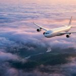 Avion de ligne volant au-dessus d'une mer de nuages au coucher du soleil.