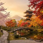 Pagode japonaise avec pont en arc, entourée de cerisiers en fleurs et d'érables aux couleurs d'automne, mont Fuji au fond.