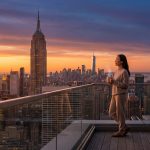 Une femme détendue sur un balcon avec vue sur New York au lever du soleil, tenant une tasse fumante.