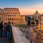 Des touristes contemplent le Colisée et Rome au coucher du soleil.
