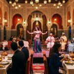Une danseuse orientale se produit sur scène devant des convives attablés dans un restaurant marocain luxueux et traditionnel.