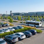 Vue aérienne du parking de l'aéroport de Beauvais avec de nombreuses voitures et une navette de bus blanche.