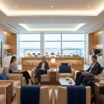 Voyageurs professionnels travaillant et se relaxant dans un salon d'aéroport moderne avec vue sur les pistes.