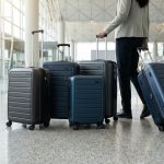 Voyageuse marchant dans un aéroport avec plusieurs valises à roulettes modernes.