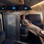 Passagère détendue dans une suite privée en classe affaires Air France, avec un repas gastronomique devant elle.