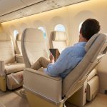 Un passager se détend dans un siège d'avion confortable avec vue sur une plage tropicale par le hublot.