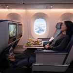 Passagers installés dans la cabine Club d'un avion Air Transat, profitant d'un repas et d'écrans individuels.