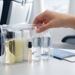 Main tenant une trousse transparente avec des flacons de liquides dans un avion.
