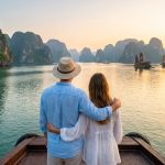Un couple admire le coucher de soleil sur les rochers karstiques de la baie d'Ha Long depuis le pont d'un bateau.
