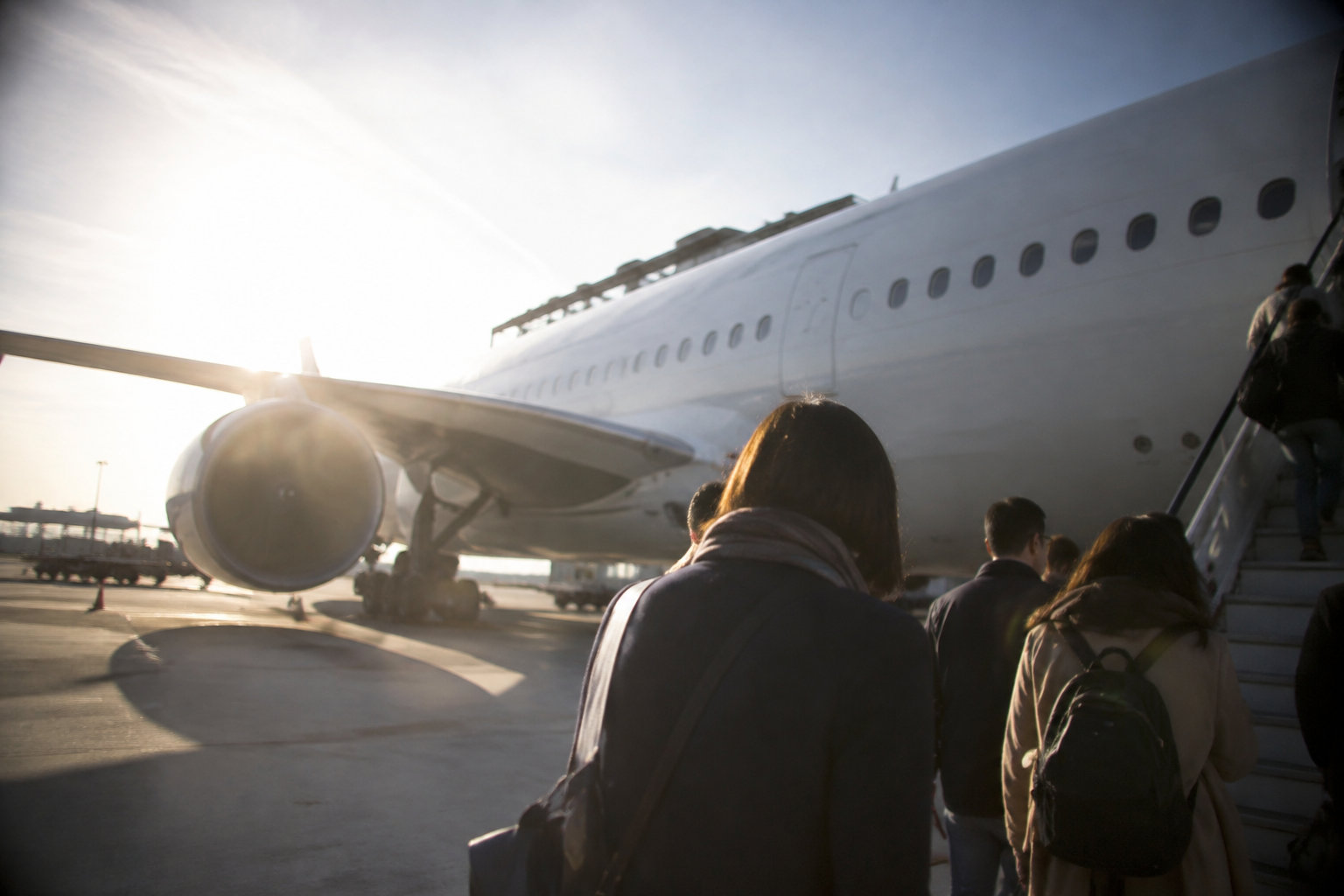 Home 34 Passagers montant à bord d'un avion par une passerelle sous un ciel ensoleillé.
