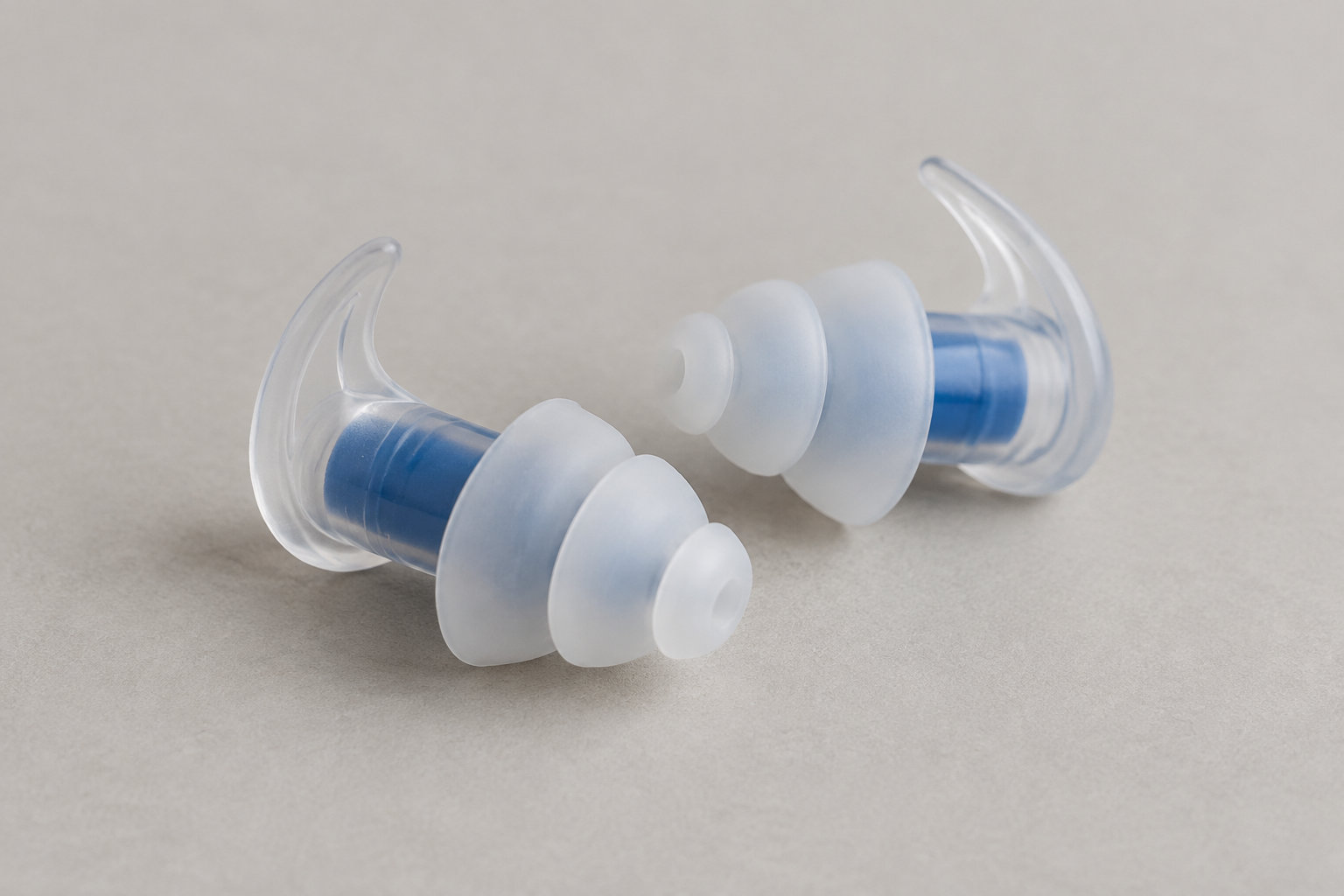 Oreilles qui bouchent en avion : solutions et astuces de pilote 5 Deux bouchons d’oreilles en silicone translucide et bleu sont posés sur une surface beige.